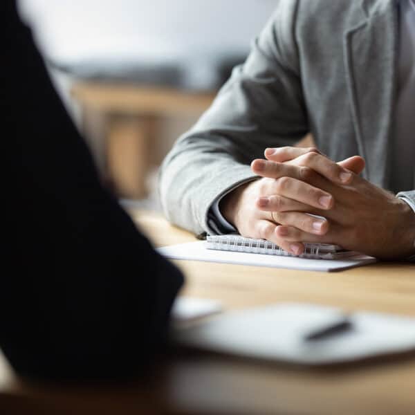 Two people sit at a meeting their clothing looks professional